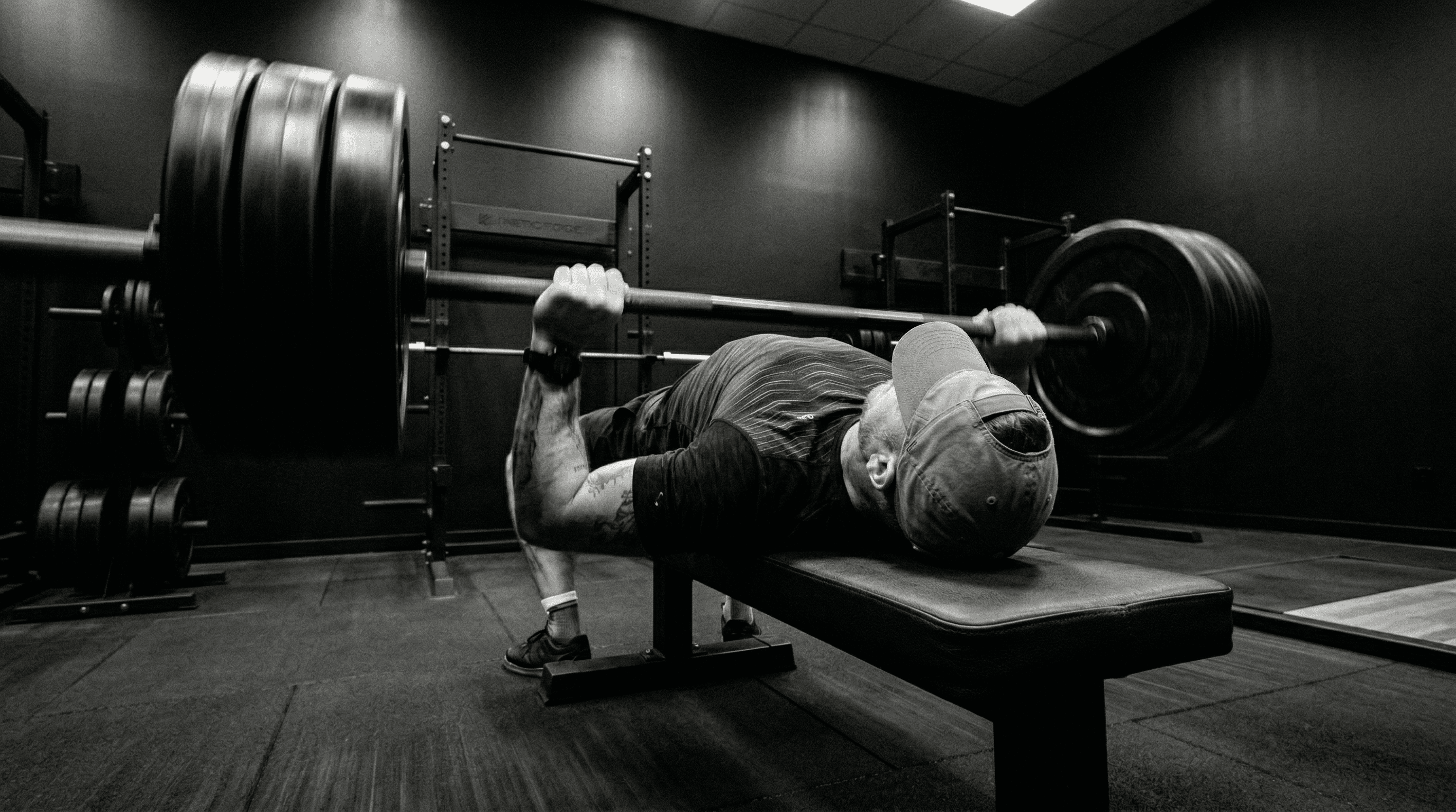 Athlete bench pressing in a dark gym